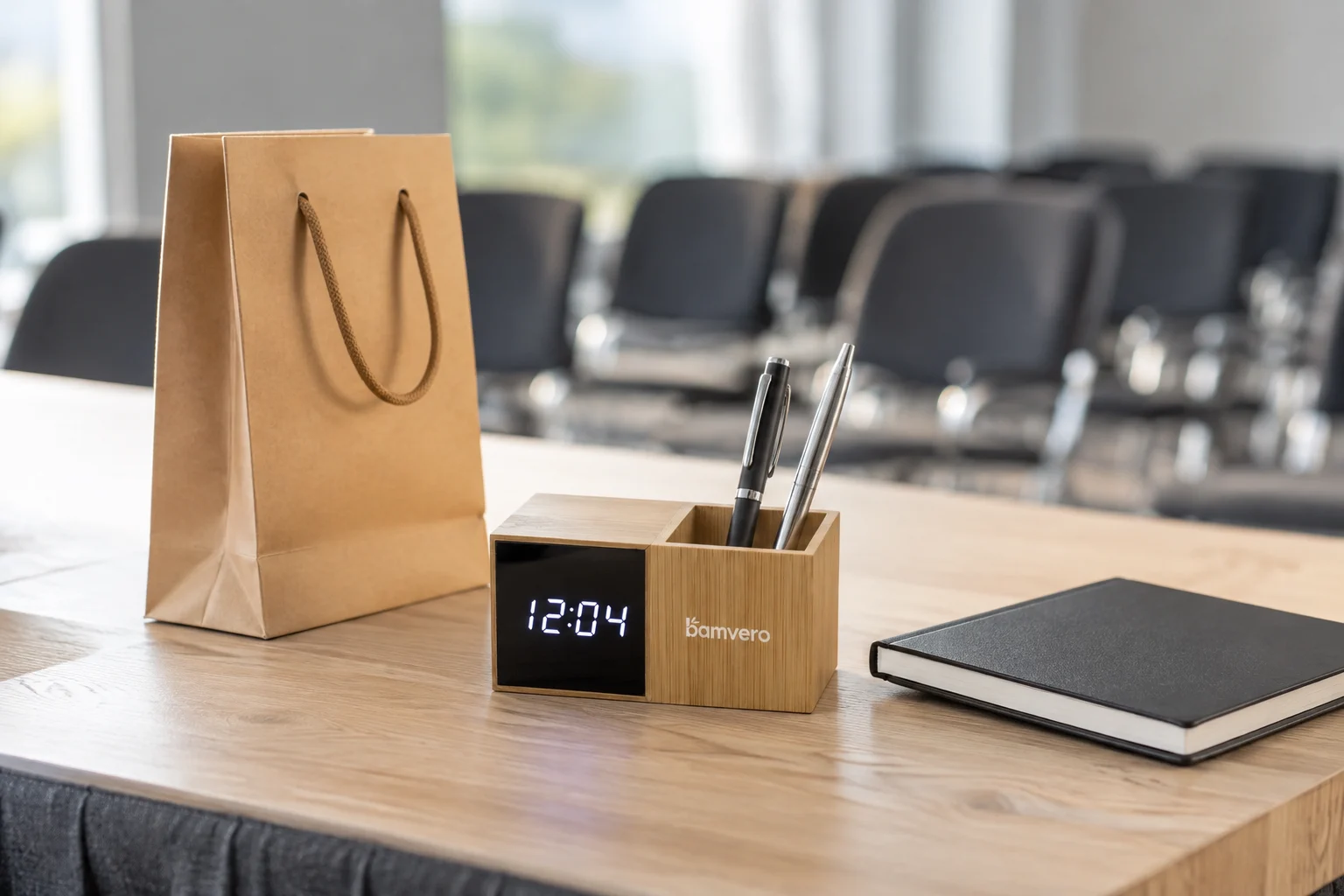 Illustrative 1293Z pen holder clock beside a gift bag and notebook on a training-event desk